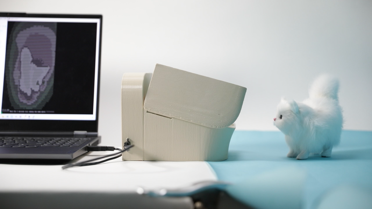 Cat.AI feeder beside a laptop displaying a detected cat